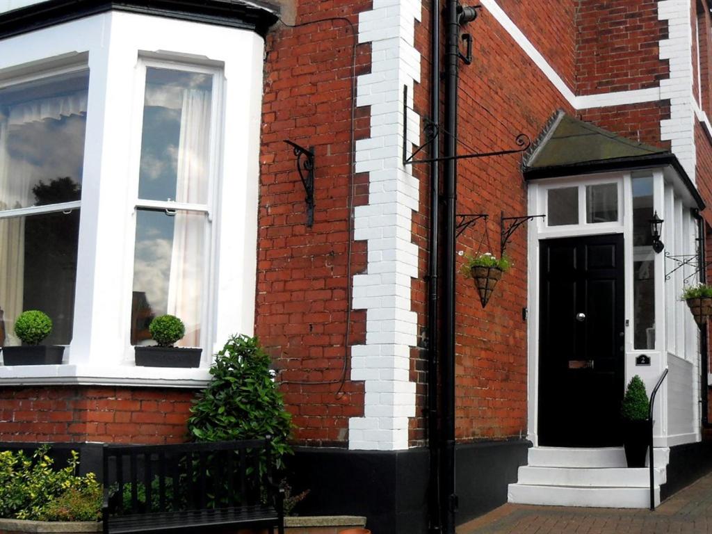 a red brick house with a black door and windows at Powys Lodge in Scarborough