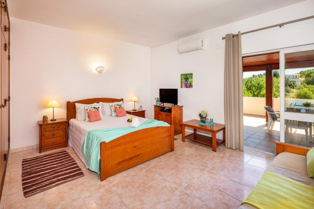 een slaapkamer met een bed en een tv en een bank bij Apartamentos Casa Brito, Boliqueime in Boliqueime