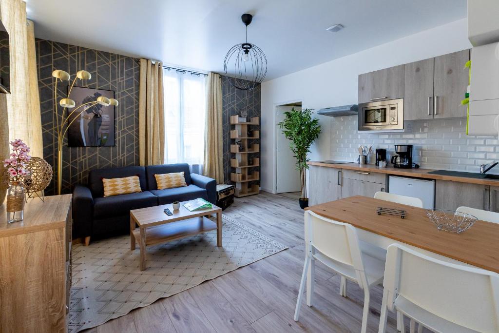 a kitchen and a living room with a couch and a table at Trankil-Apparts Centre 2 in Saint-Quentin