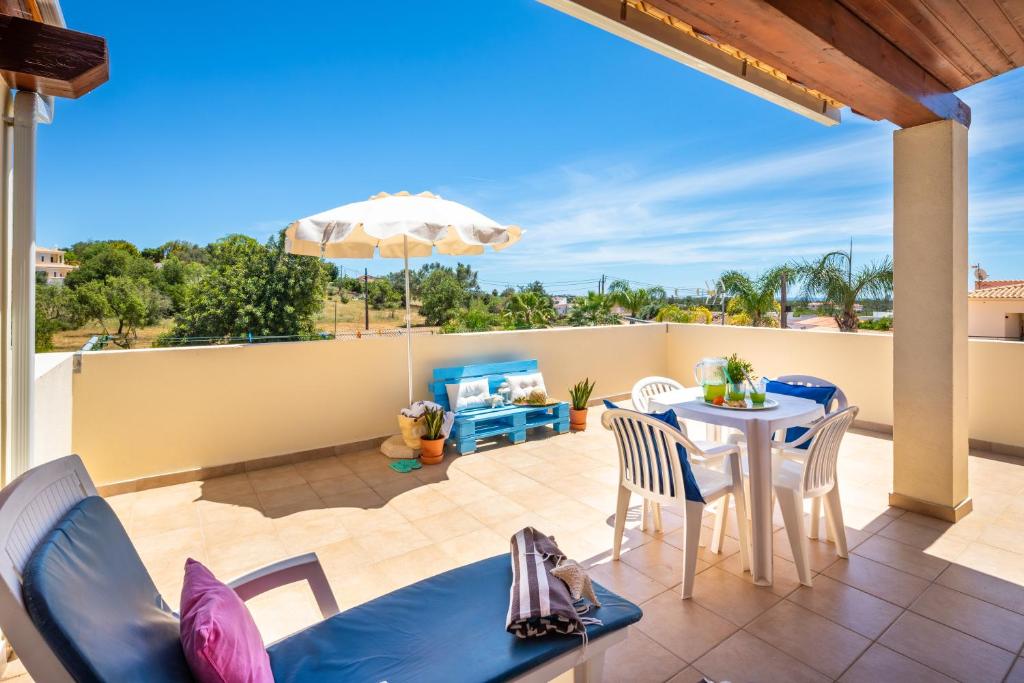 un patio avec une table, des chaises et un parasol dans l'établissement Apartamentos Casa Brito, Boliqueime by AlgarveBlossom, à Boliqueime