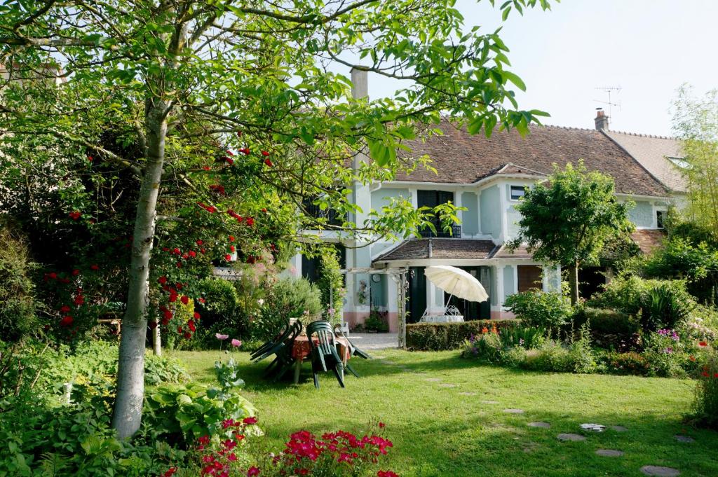 una casa blanca con un patio con flores en Chambres d'hôtes Le Grand Air - Les châteaux de la Brie aux portes de Paris, en Ozouer-le-Voulgis