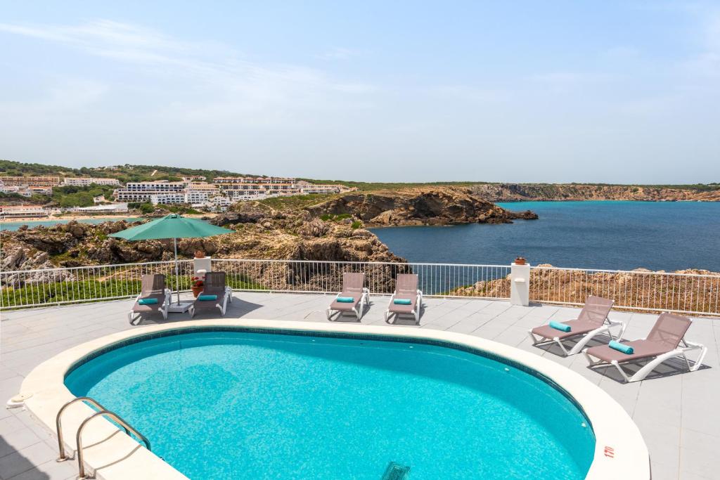 una piscina con sillas y vistas al océano en Villa Margarita, en Es Mercadal