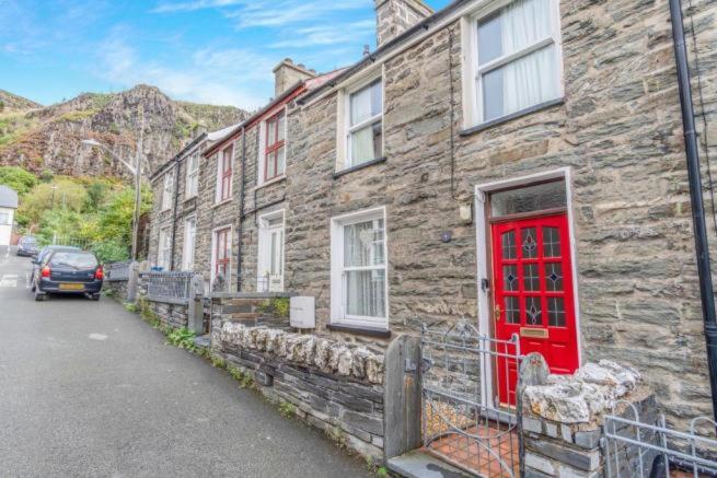 a stone house with a red door on a street at The Sidings Wales in Blaenau-Ffestiniog
