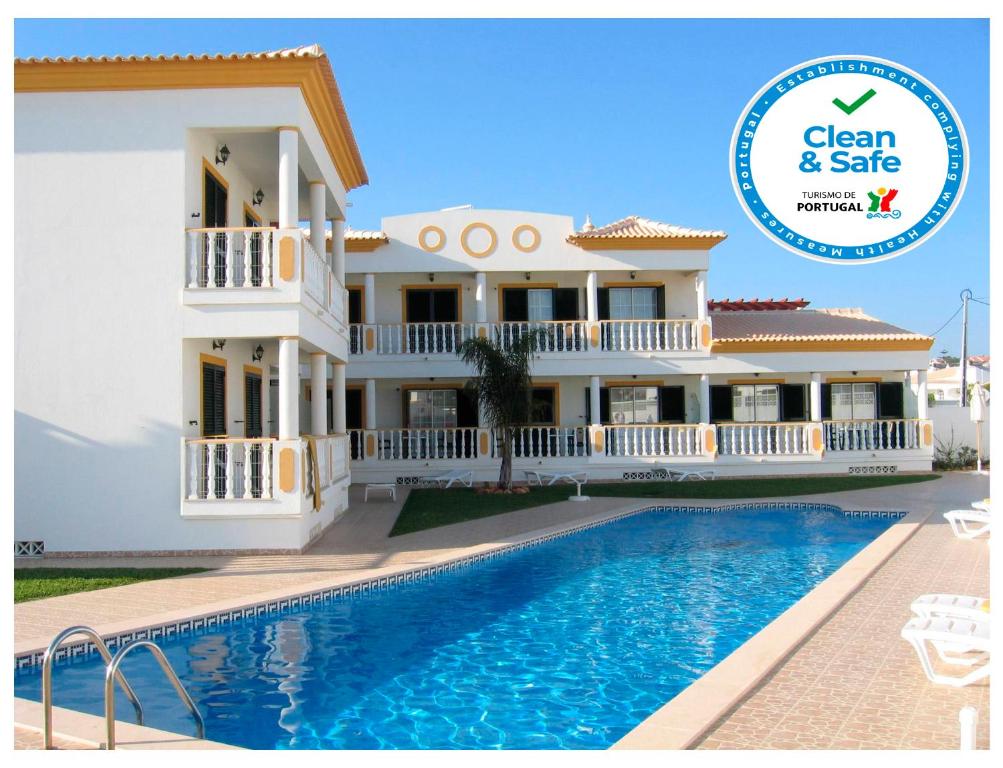 een villa met een zwembad en het schone en veilige logo bij Apartamentos Solar Veiguinha in Albufeira