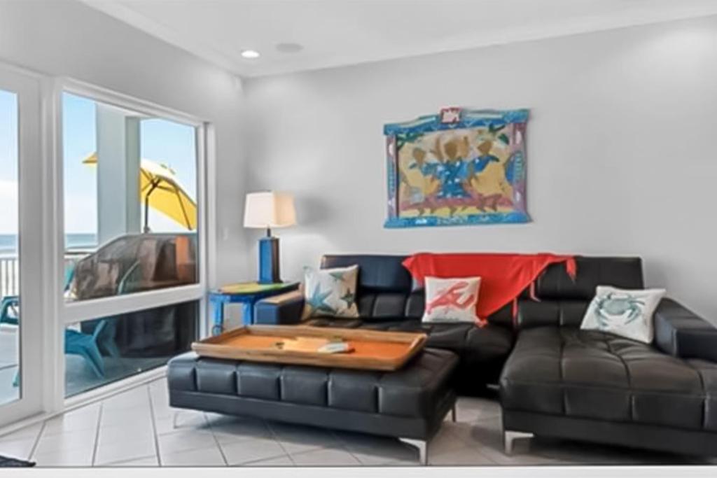 sala de estar con sofá de cuero negro y mesa en Big O Beach - White Sands Townhomes, en Pensacola Beach