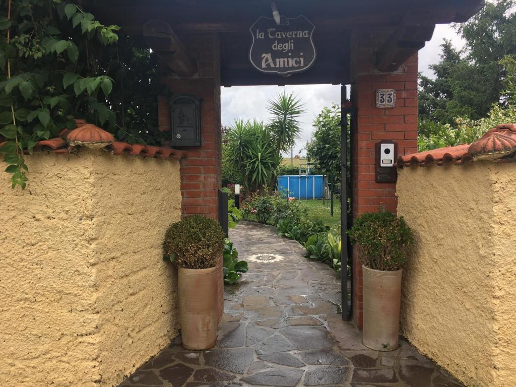 an entrance to a garden with potted plants and a sign at Tavernamici in Anguillara Sabazia