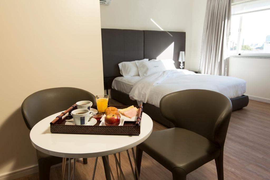 a hotel room with a bed and a table with a tray of food at Way Apartamentos in Montevideo