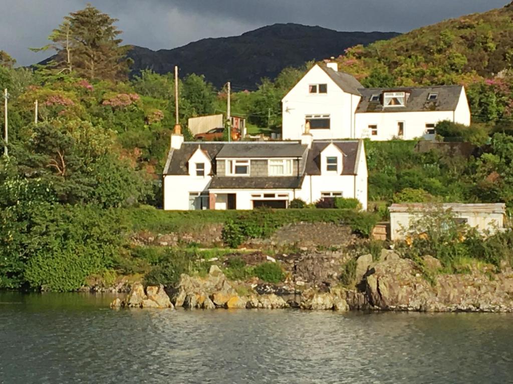 a house on a hill next to a body of water at Hillside in Kyleakin