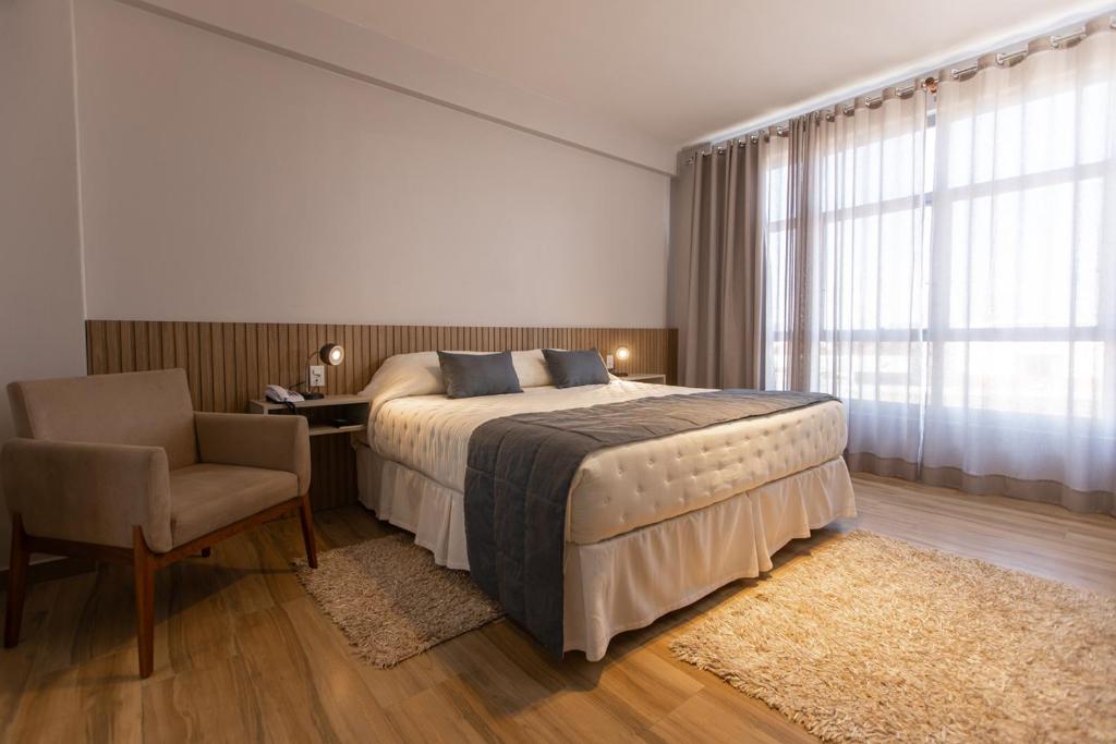 a bedroom with a bed and a desk and a chair at BM Hotel in São Sebastião do Paraíso