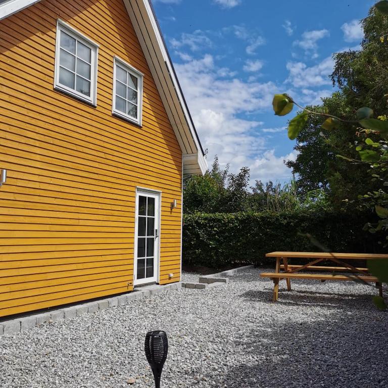 a yellow building with a bench next to it at Samsø værelseudlejning in Tranebjerg