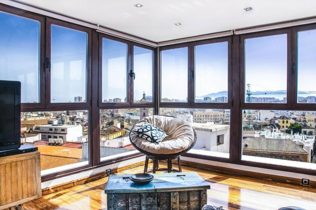 una sala de estar con grandes ventanas y una silla en Malagaflat Design Loft City Views, en Málaga