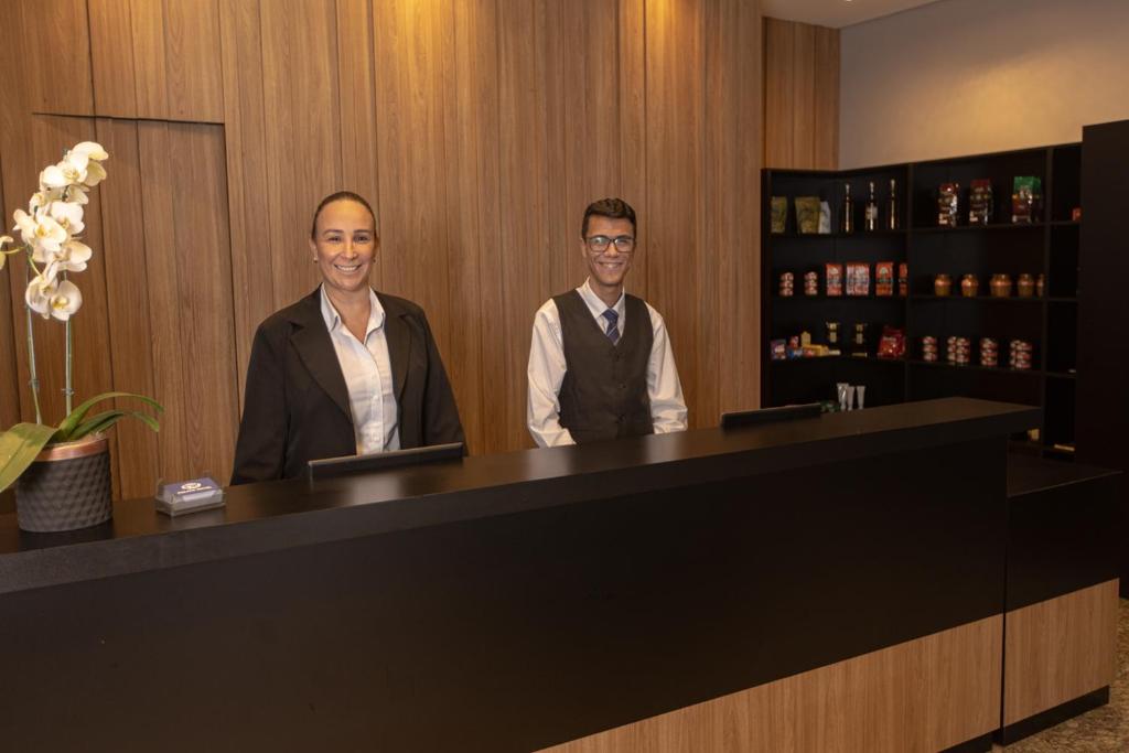 two men standing in front of a counter in a bar at BM Hotel in São Sebastião do Paraíso