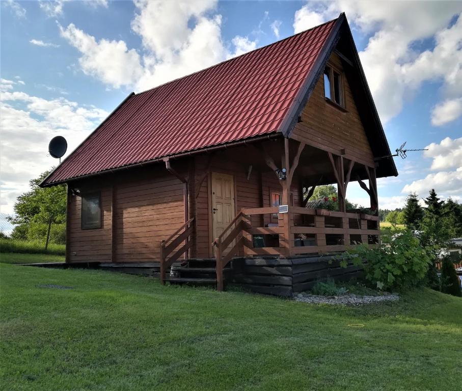 a large wooden cabin with a red roof at PILGRIM domek gościnny w Gietrzwałdzie na Warmii in Gietrzwałd