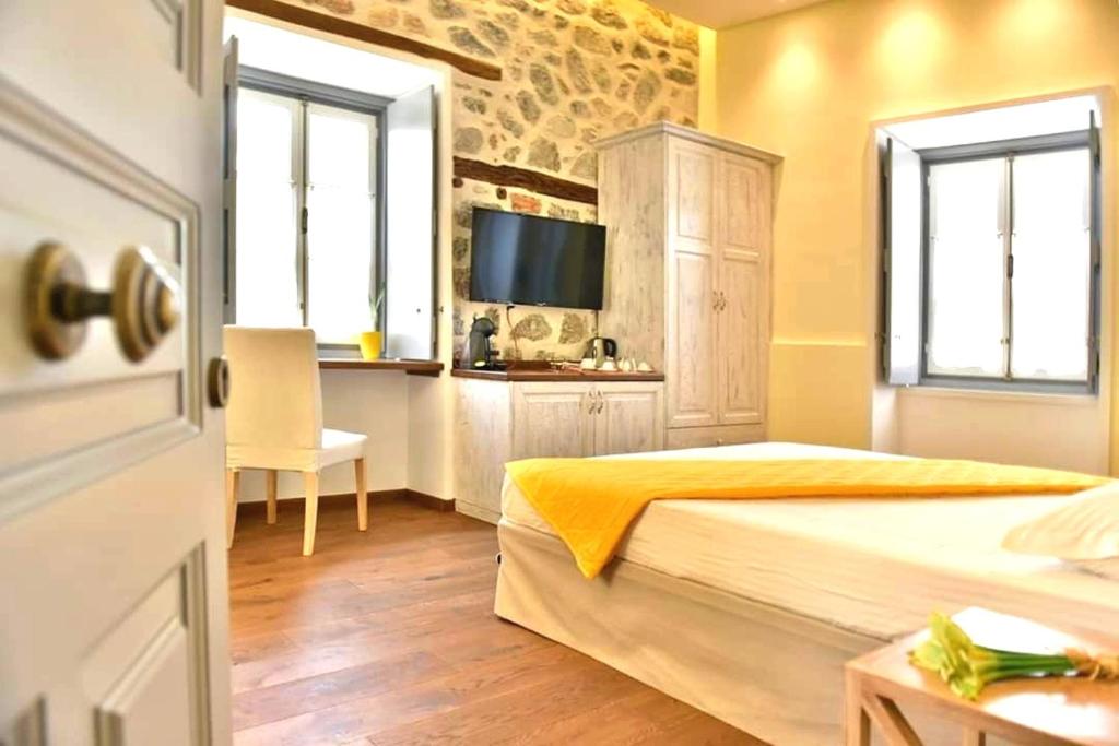 a bedroom with two beds and a television in it at Manolia in Hydra