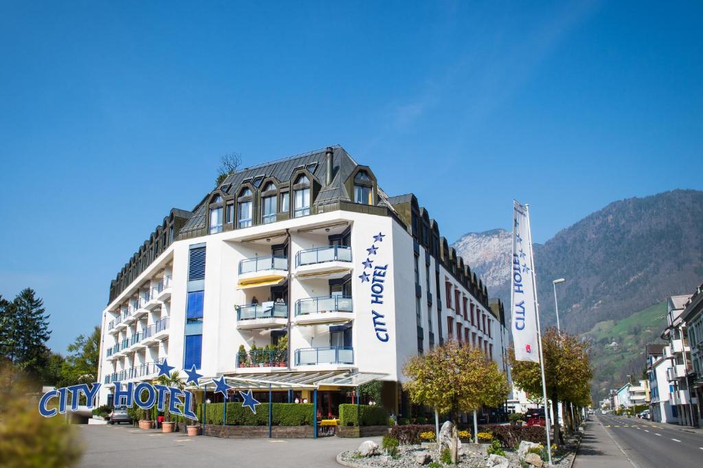 un bâtiment dans une rue avec des montagnes en arrière-plan dans l'établissement City Hotel, à Brunnen