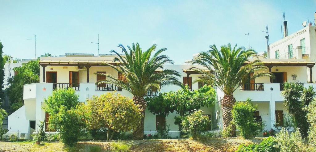 a building with palm trees in front of it at Mavrikou Helen Apartments in Skiros