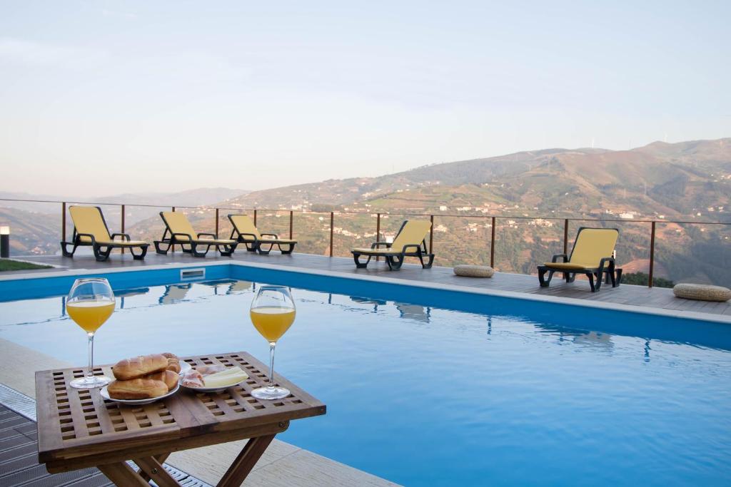 a table with two glasses of wine next to a pool at Vila Douro Guesthouse in Mesão Frio