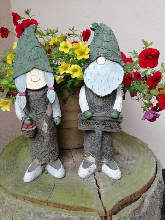 NeukirchenにあるKleines Haus mit Geschichteの花の鉢の横に二人の人形が立っている