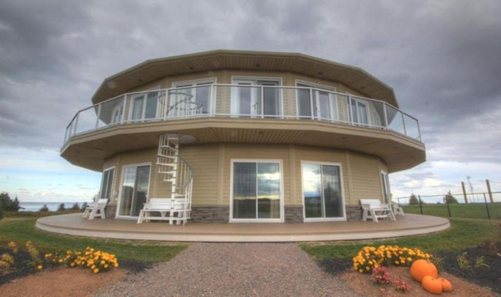 a round house with two chairs and a ladder on it at Around the Sea - Cana da's Rotating House, Suites & Tours in North Rustico