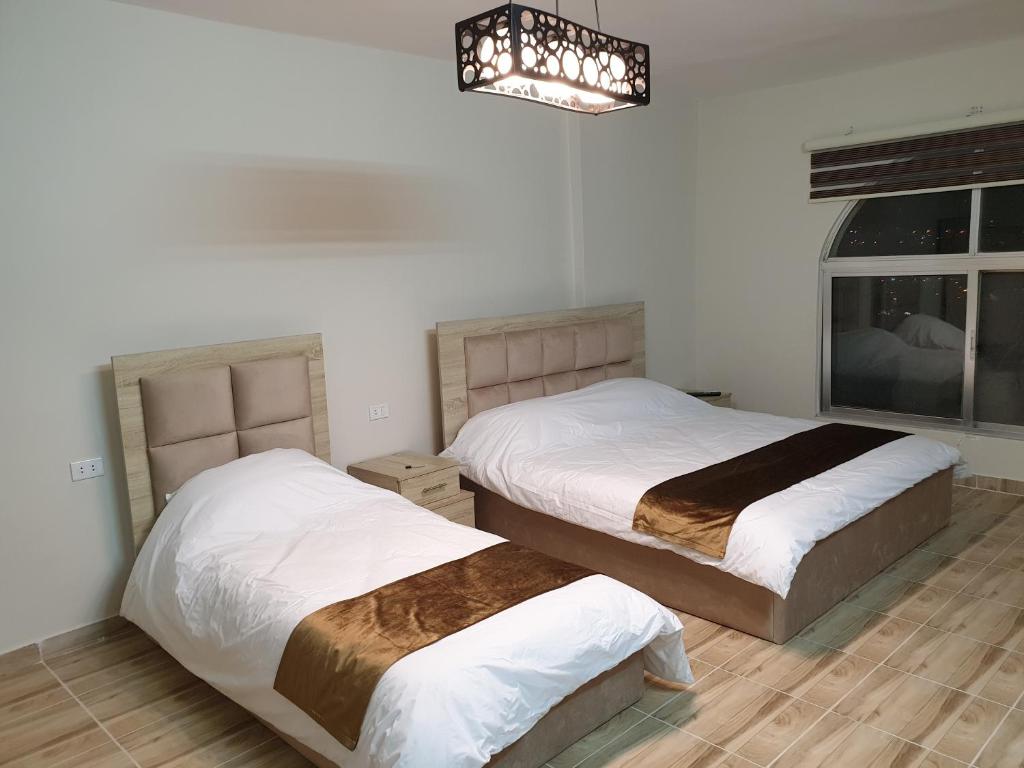 - une chambre avec 2 lits et un lustre dans l'établissement atoom studio, à Jerash