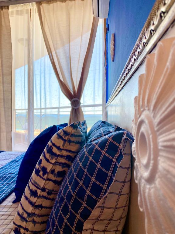 a bedroom with pillows on a bed with a window at Свети Зосим in Sozopol