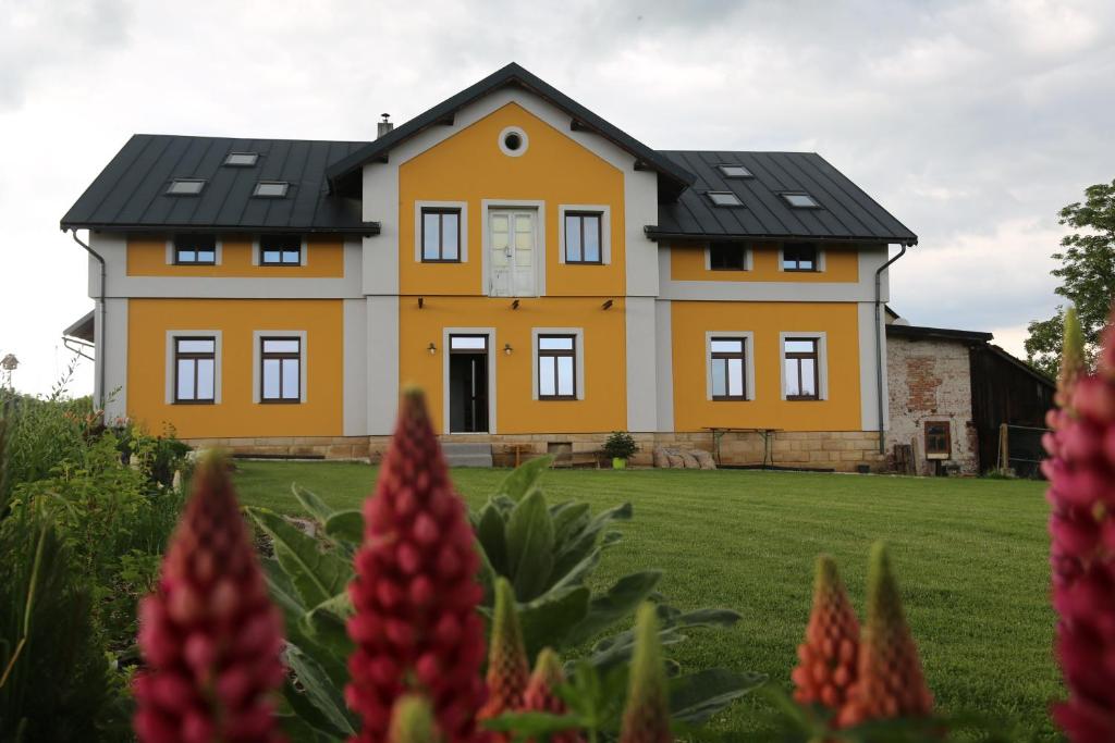 une maison jaune avec un toit noir dans l'établissement Ubytování na statku - Střížovice č.p. 11, à Pěnčín