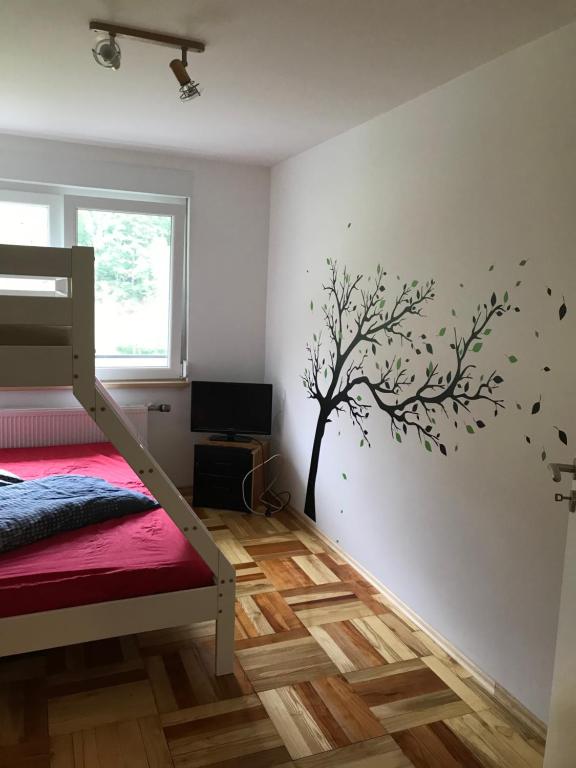 a bedroom with a tree stenciled on the wall at Ferienhaus am Wald in Wendehausen