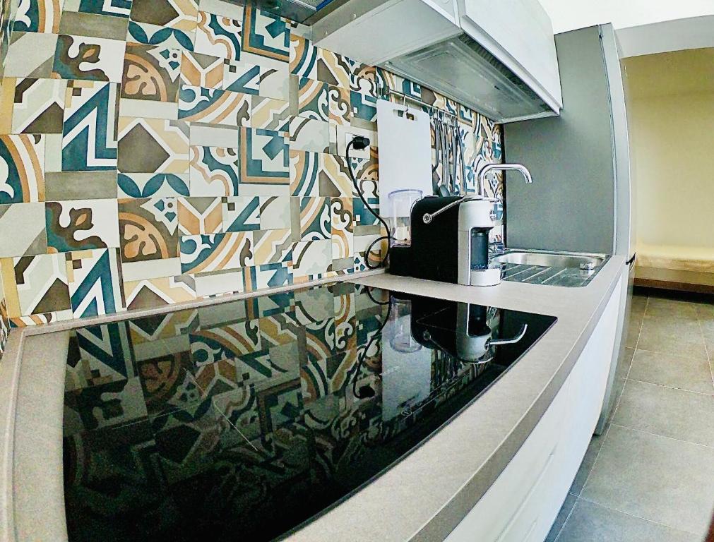 una cucina con parete a mosaico e lavandino di "Sweet Life" Casa Vacanze a Città di Lipari