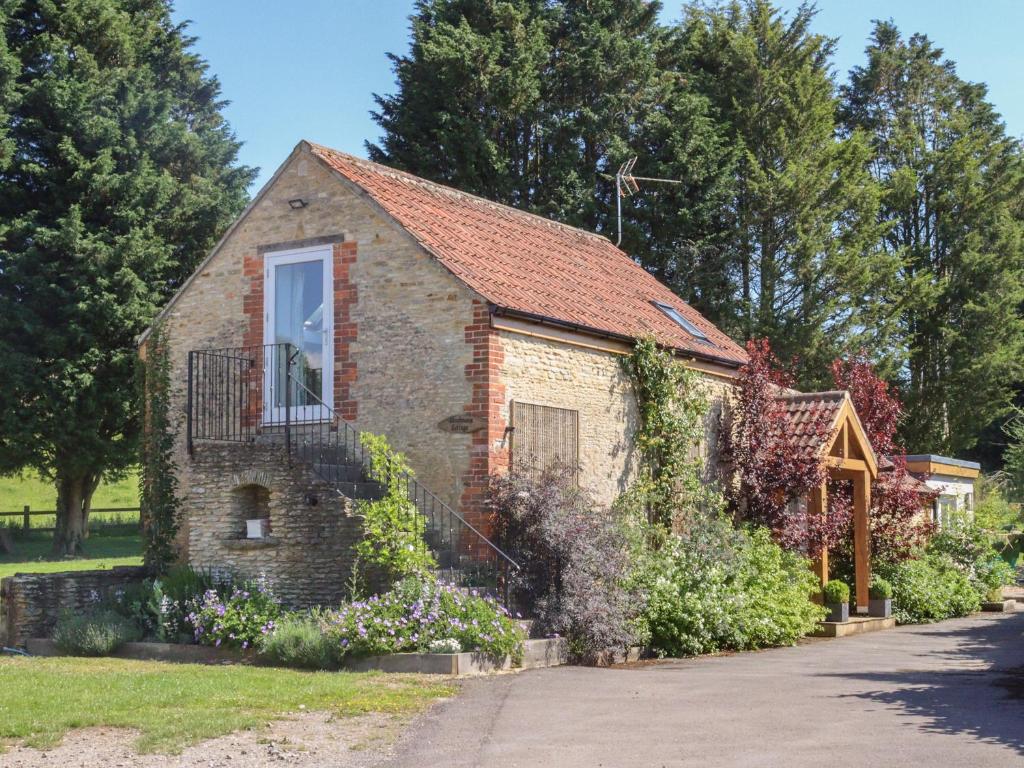 uma casa de tijolos com uma janela e uma varanda em Woodmans Cottage Nables Farm em Chippenham