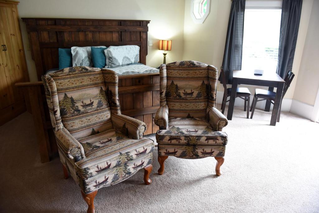 a bedroom with a bed and a pair of chairs at Heidi Motel - Helen in Helen