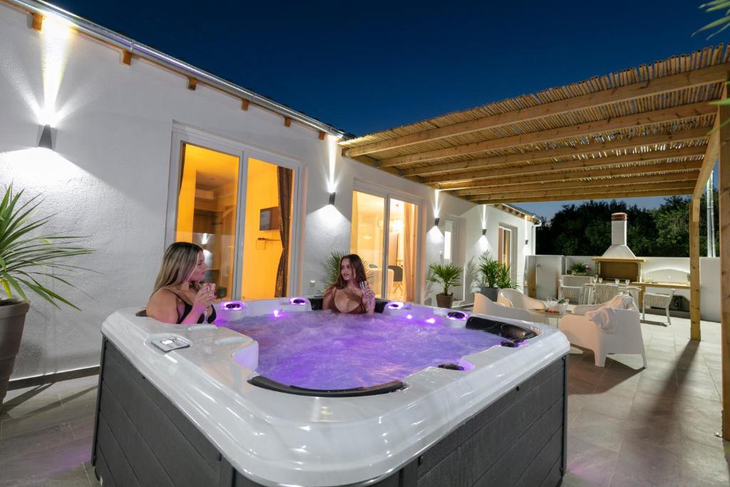 two women sitting in a hot tub on a patio at Jacuzzi deluxe villa in Skala Sotiros