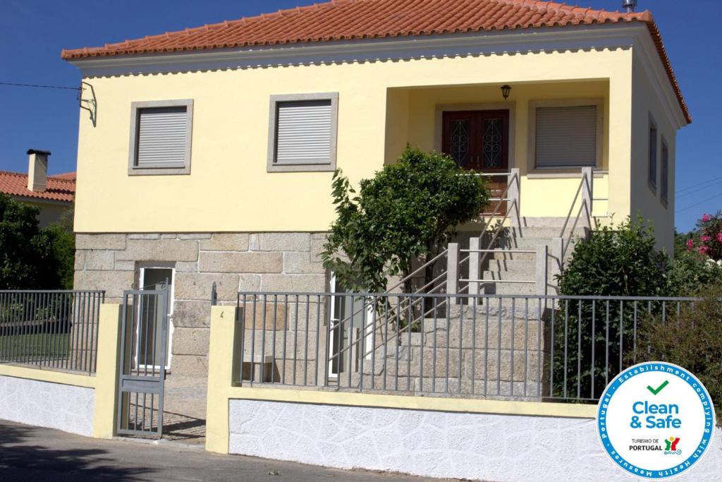 una casa amarilla con una puerta y un cartel que diga limpia y segura en Casa do Regueirinho en Vila Nova de Cerveira