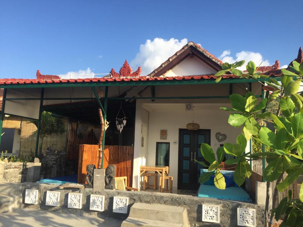 een huis met een veranda met een dak bij Isin Gumi Homestay in Amed