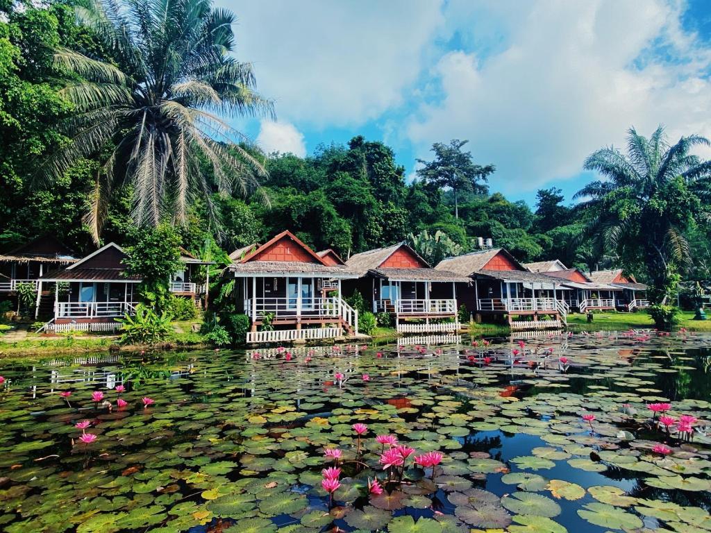 un étang avec un tas de maisons et de fleurs. dans l'établissement Holiday Resort - SHA Plus, à Ko Yao Noi