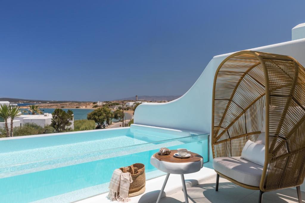 a villa with a pool and a rattan chair and a table at Lilly Residence-All Sea View Suites, Adults Only in Naousa