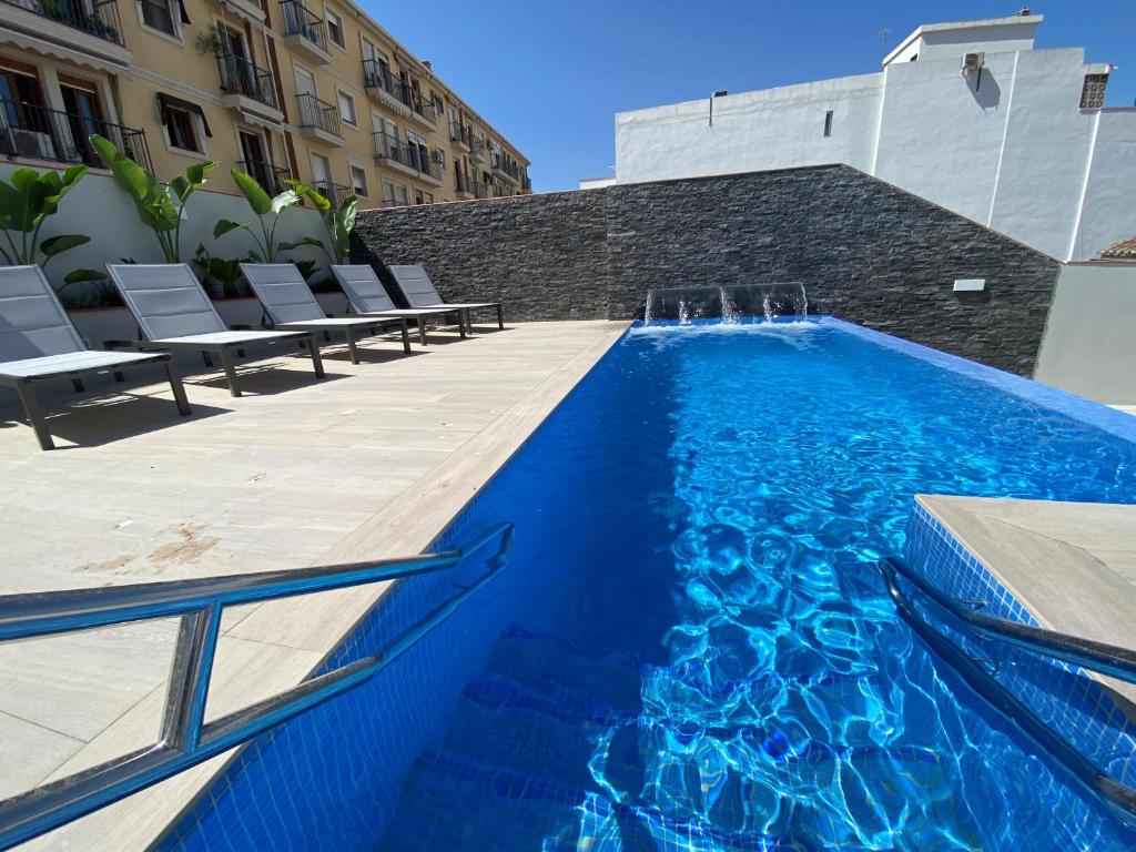 a swimming pool with a blue pool table and blue chairs at Hotel Brö-Adults Only in Málaga
