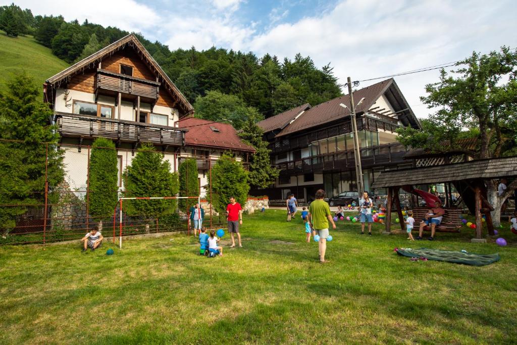 a group of people playing in the grass in front of a house at Pension Mama Cozonacilor in Bran