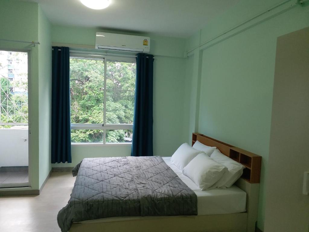 a bedroom with a bed and a large window at DD Garden Apartment 2 in Bangkok