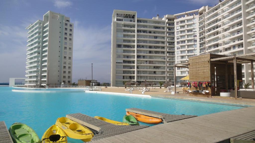 a swimming pool with kayaks and chaises in front of buildings at Resort Urbano Laguna del Mar in La Serena