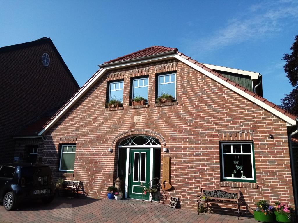 a red brick house with a green door and windows at Friesenhof Riepe in Ihlow