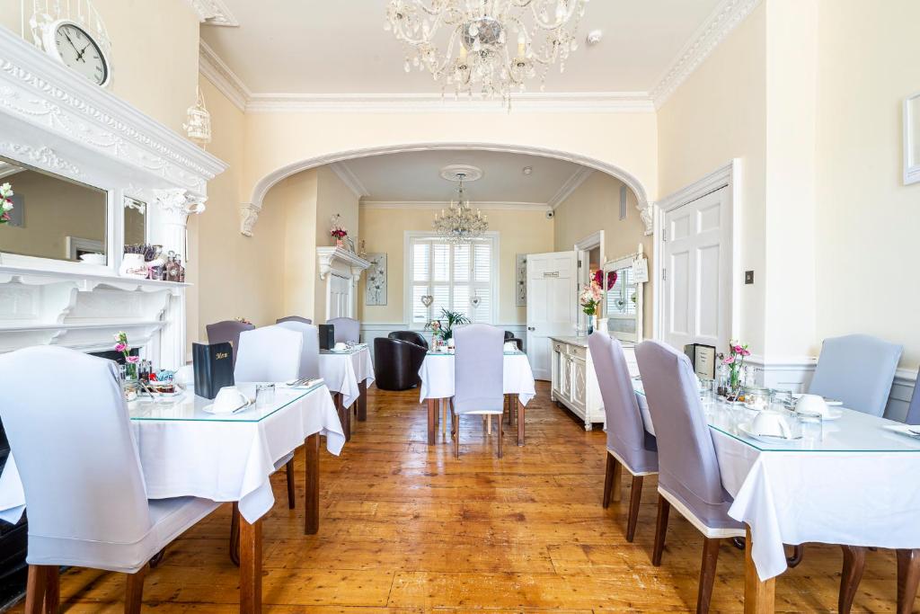 a dining room with white tables and chairs and a chandelier at Hamiltons Boutique Hotel in Southend-on-Sea