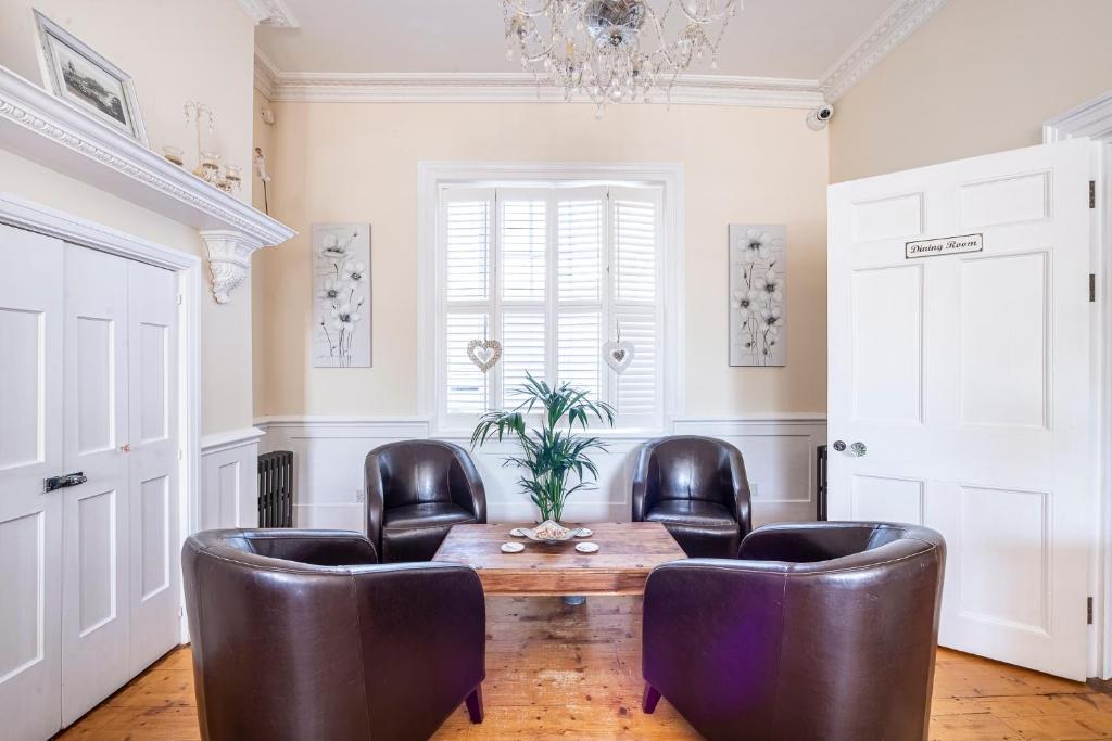 a living room with leather chairs and a wooden table at Hamiltons Boutique Hotel in Southend-on-Sea