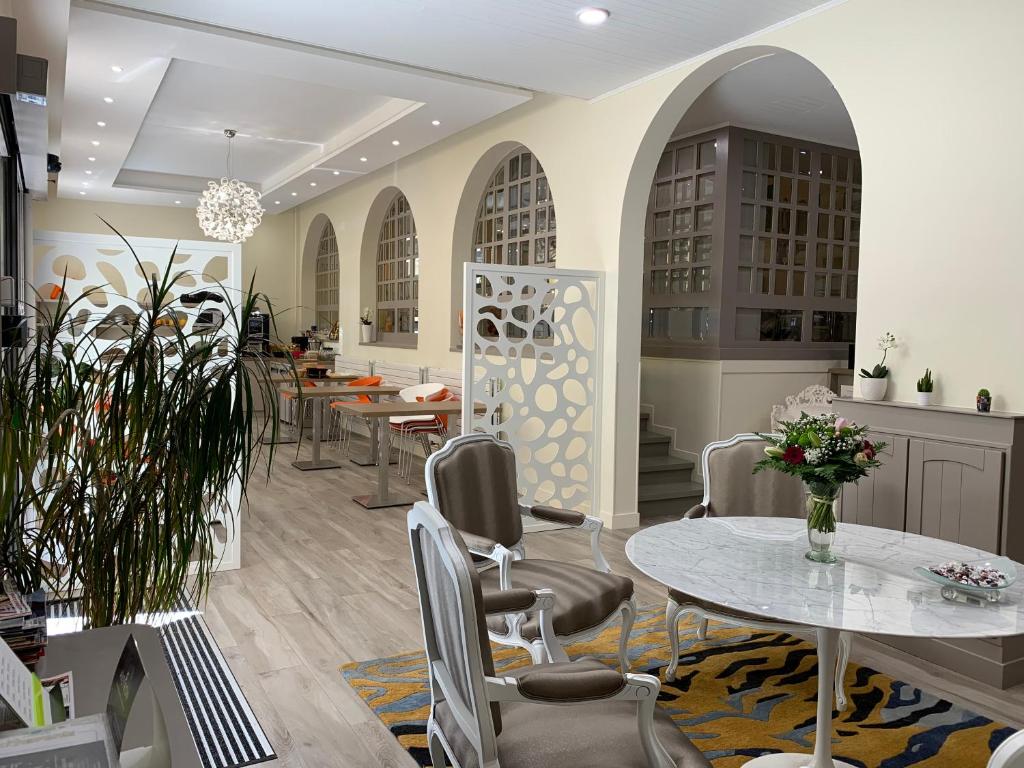 a dining room with tables and chairs and a kitchen at Hotel Biney in Rodez