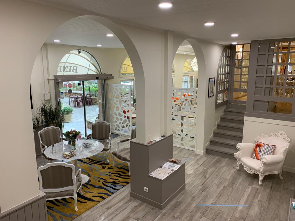 een lobby met een tafel en stoelen en een trap bij Hotel Biney in Rodez