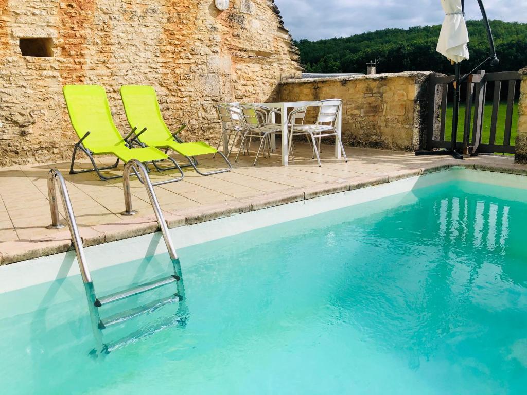 einen Pool mit 2 Stühlen, einem Tisch, einem Tisch und Stühlen in der Unterkunft Gîte Chez Zoa in Gignac