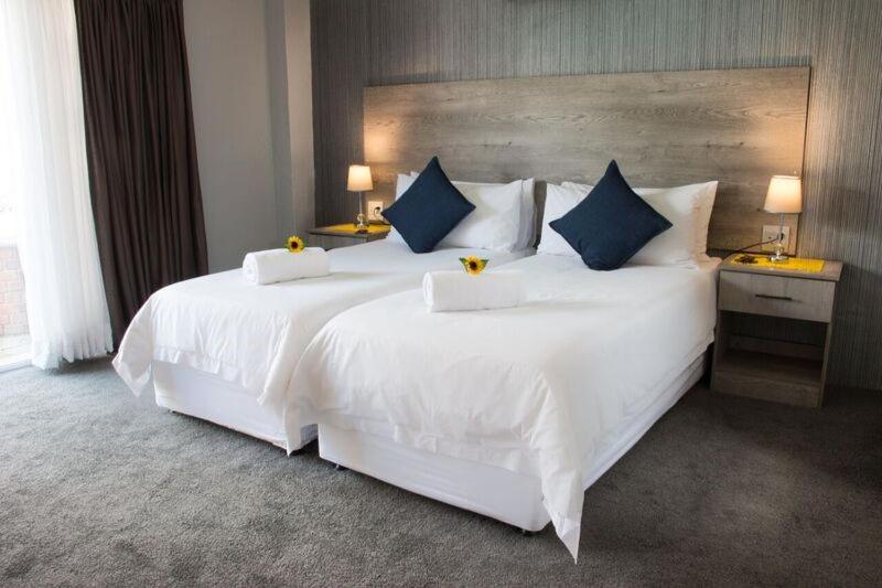 a bedroom with a large white bed with blue pillows at McAllisters on 8th in Durban