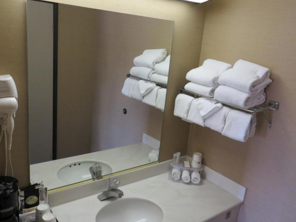 a bathroom with a sink and a mirror and towels at Howard Johnson by Wyndham Torrance in Torrance