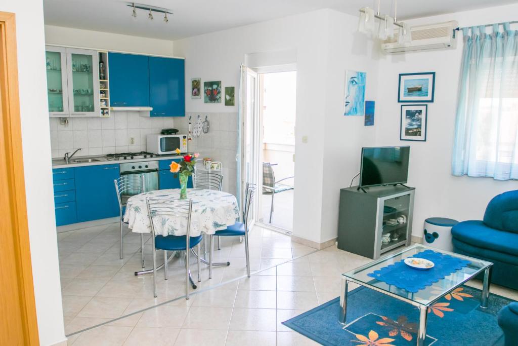 cocina y sala de estar con mesa y armarios azules en Lavanda Apartment, en Fažana