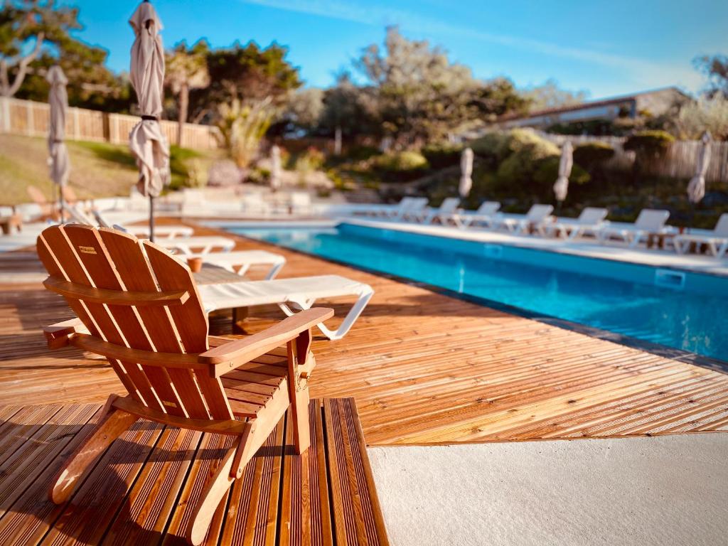 une terrasse en bois avec une chaise et une piscine dans l'établissement Hôtel Île de Lumière, à La Cotinière