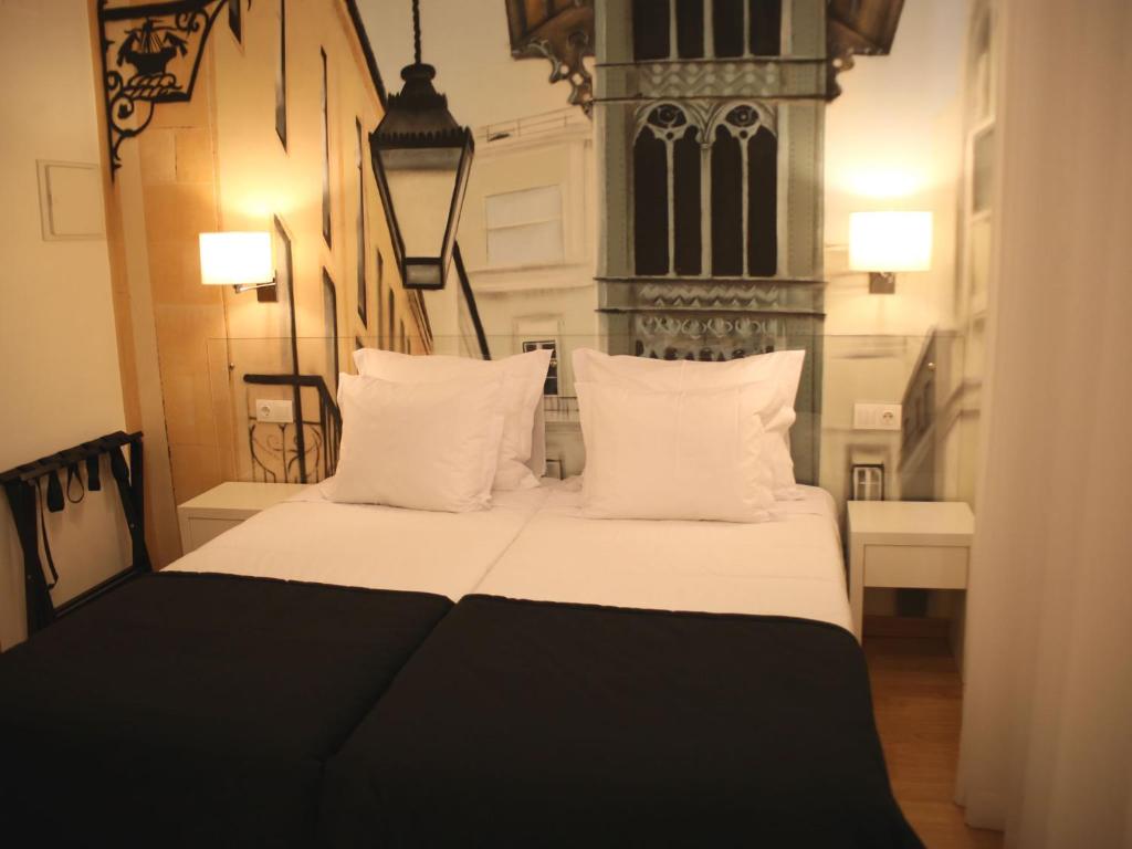 una camera da letto con letto, lenzuola e cuscini bianchi di Lisbon Style a Lisbona